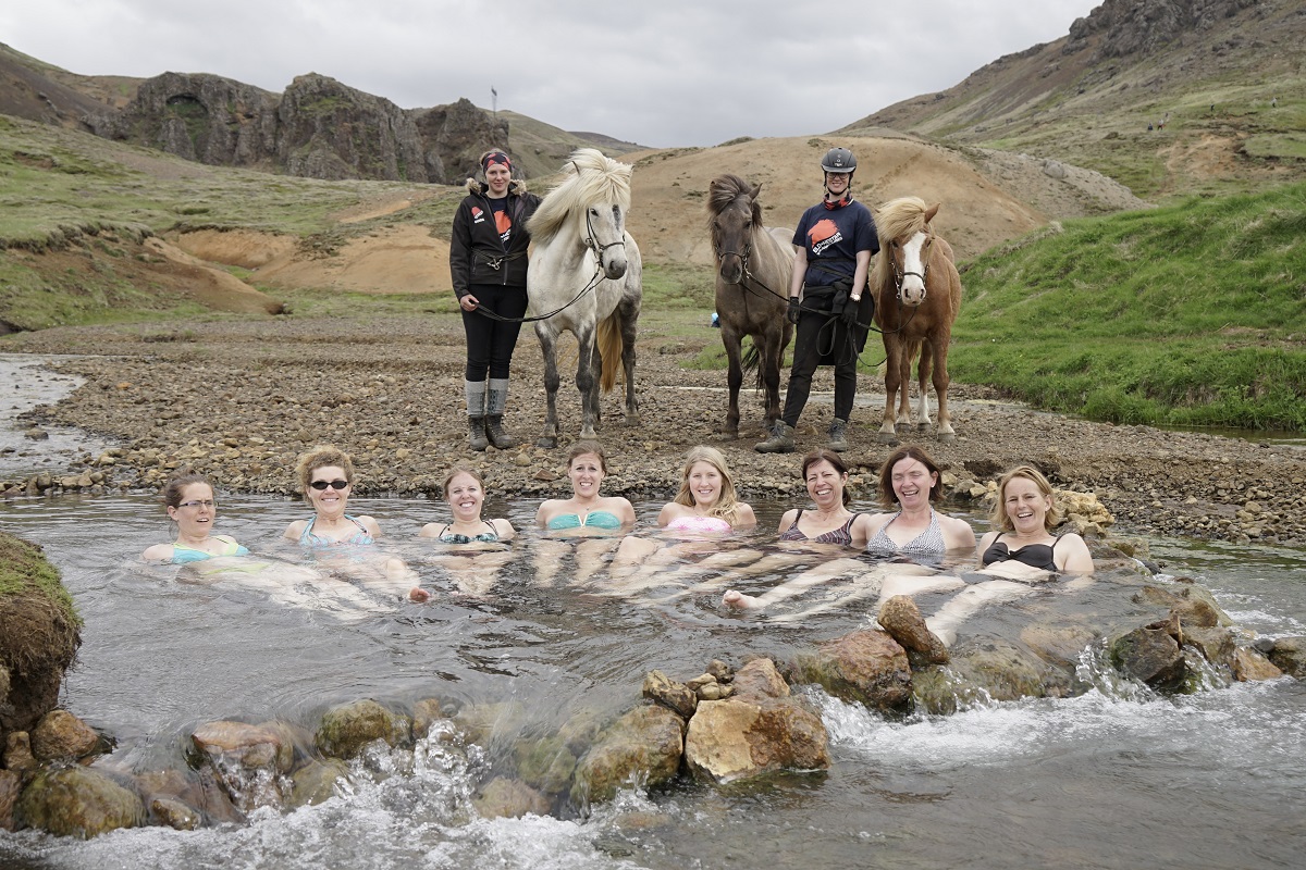 Reizigers badderen in een geothermisch bad tijdens een paardrijtour.