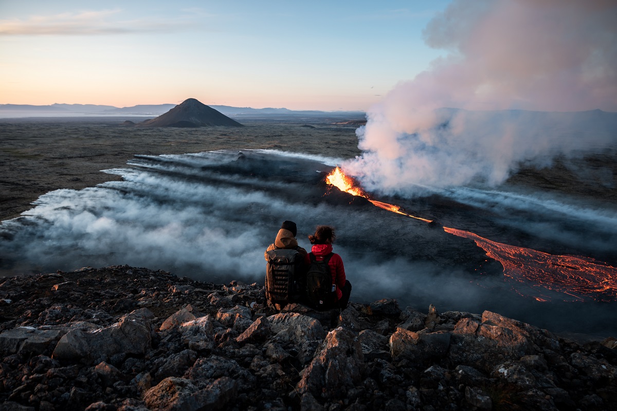 Een koppel kijkt uit over het uitgestrekte landschap in Reykjanes met de vulkaan Litli-Hrutur die is uitgebarsten. 