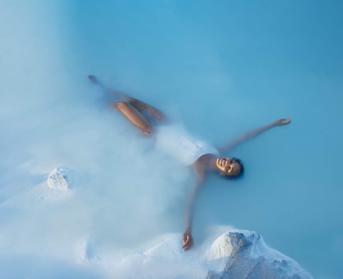 Een vrouw is aan het drijven en relaxen in de Blue Lagoon, een warmwaterbad in Reykjanes IJsland.