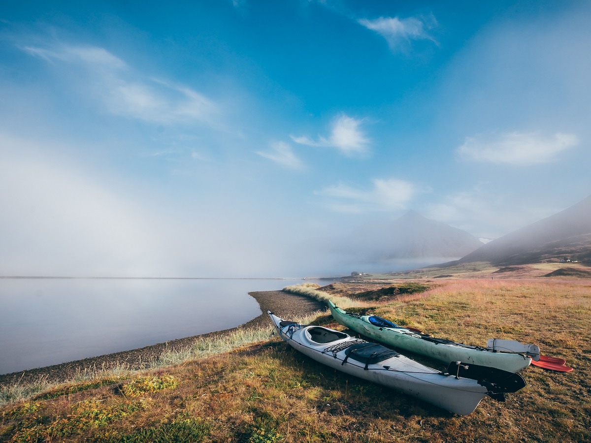 Twee kajaks liggen op de kant langs rustig water in IJsland.