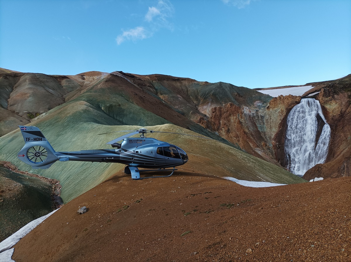 Een helikopter is tijdens een tour geland bij een waterval.