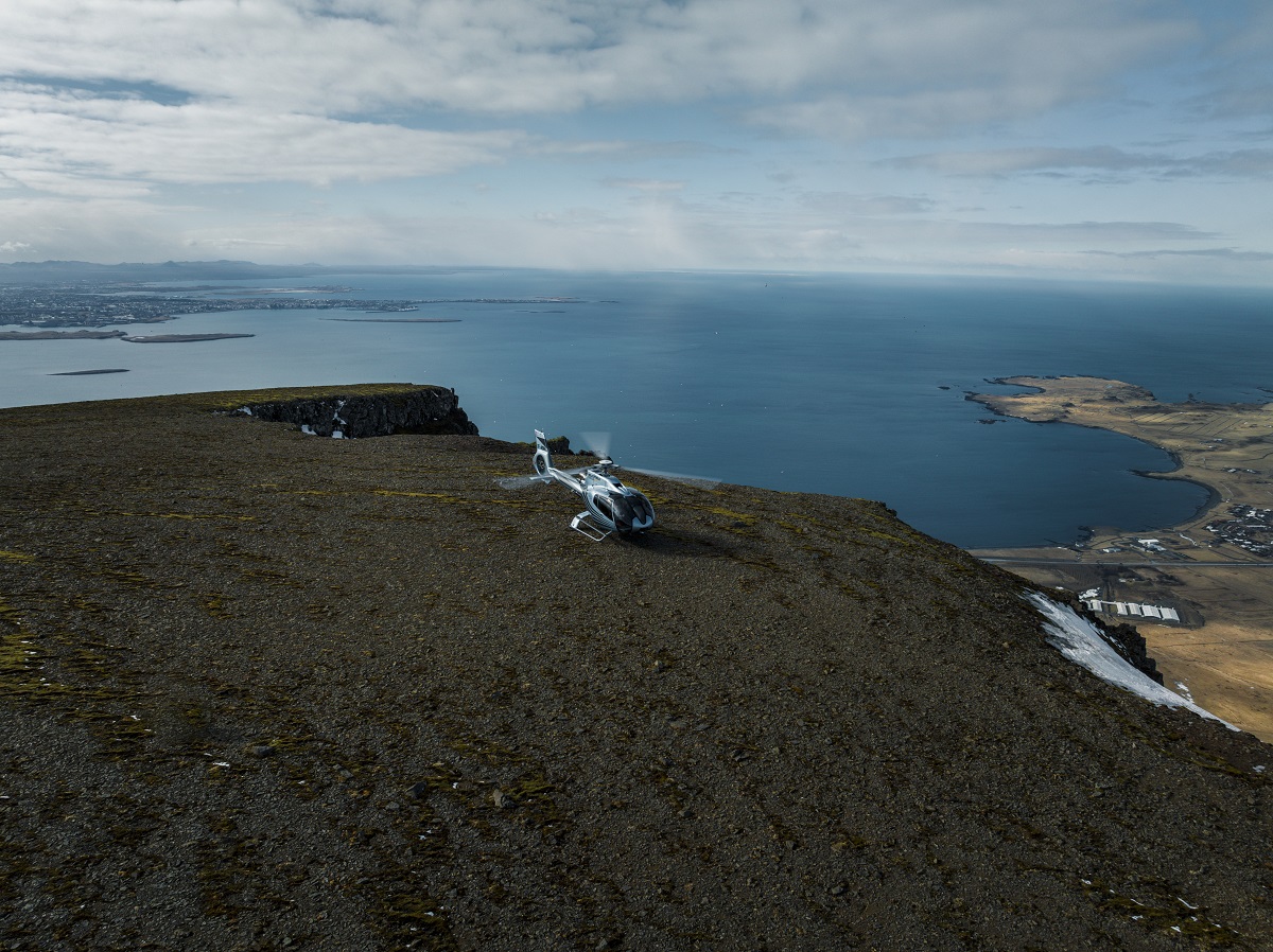 Een helicopter op een top met uitzicht over Reykjavik.
