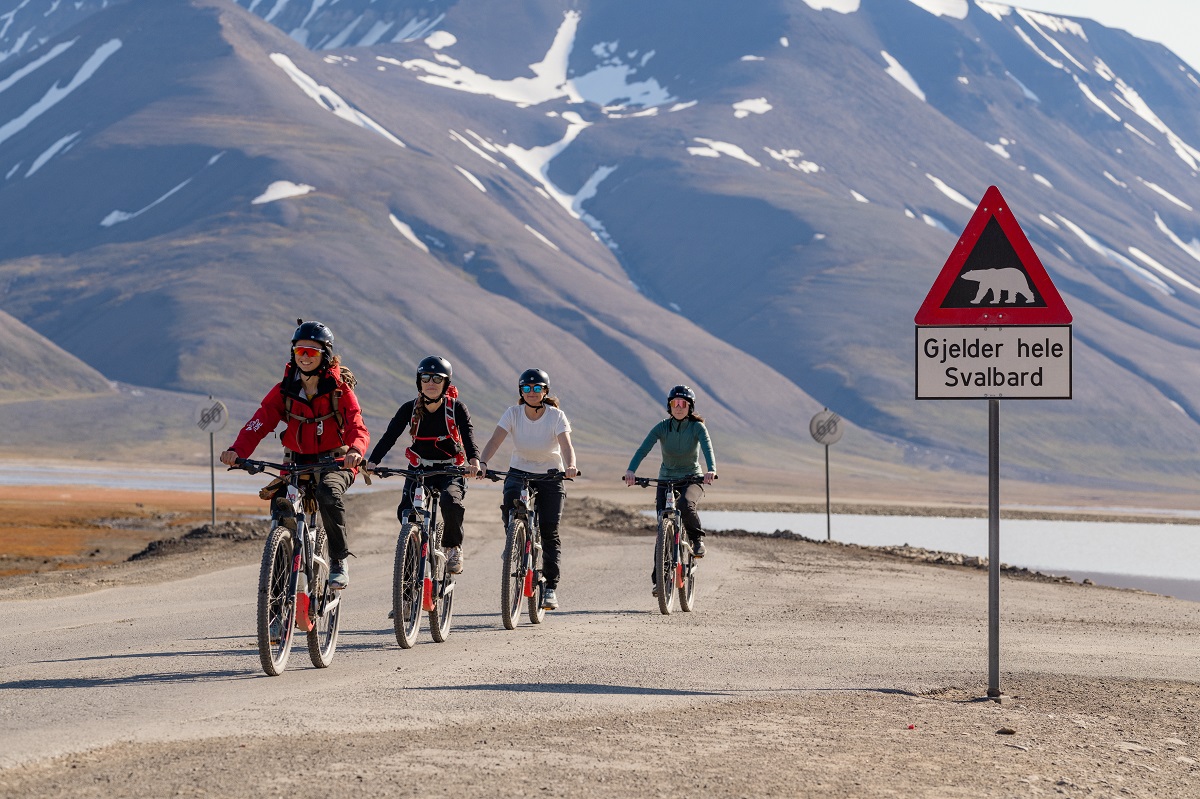 Vier fietsers op elektrische fietsen in Longyearbyen, Spitsbergen.